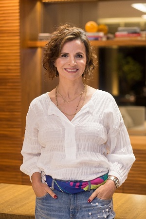 Adriana está com as mãos nos bolsos olhando para a frente