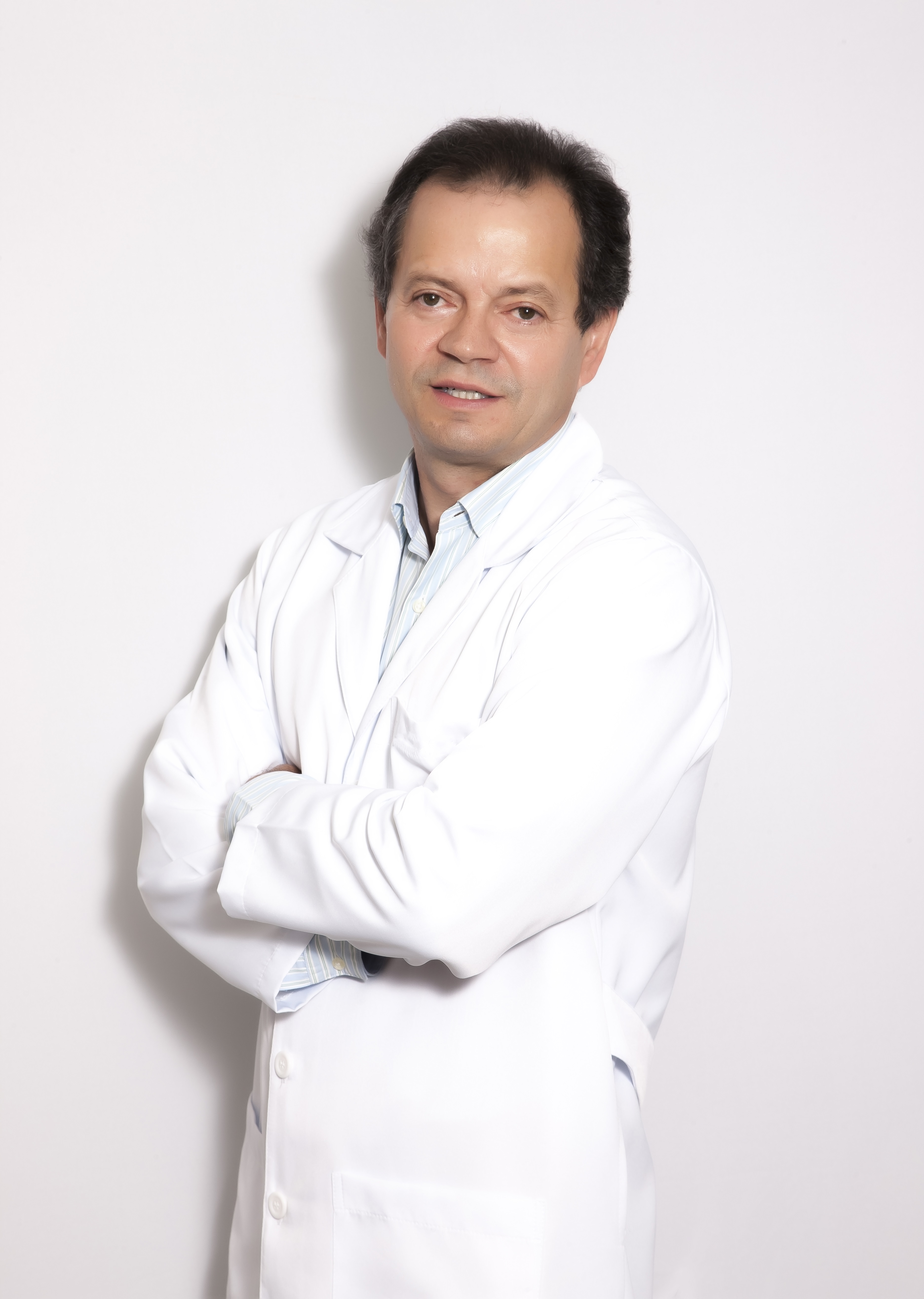 Amândio Fernandes está em pé, de braços cruzados, usando roupa branca. 