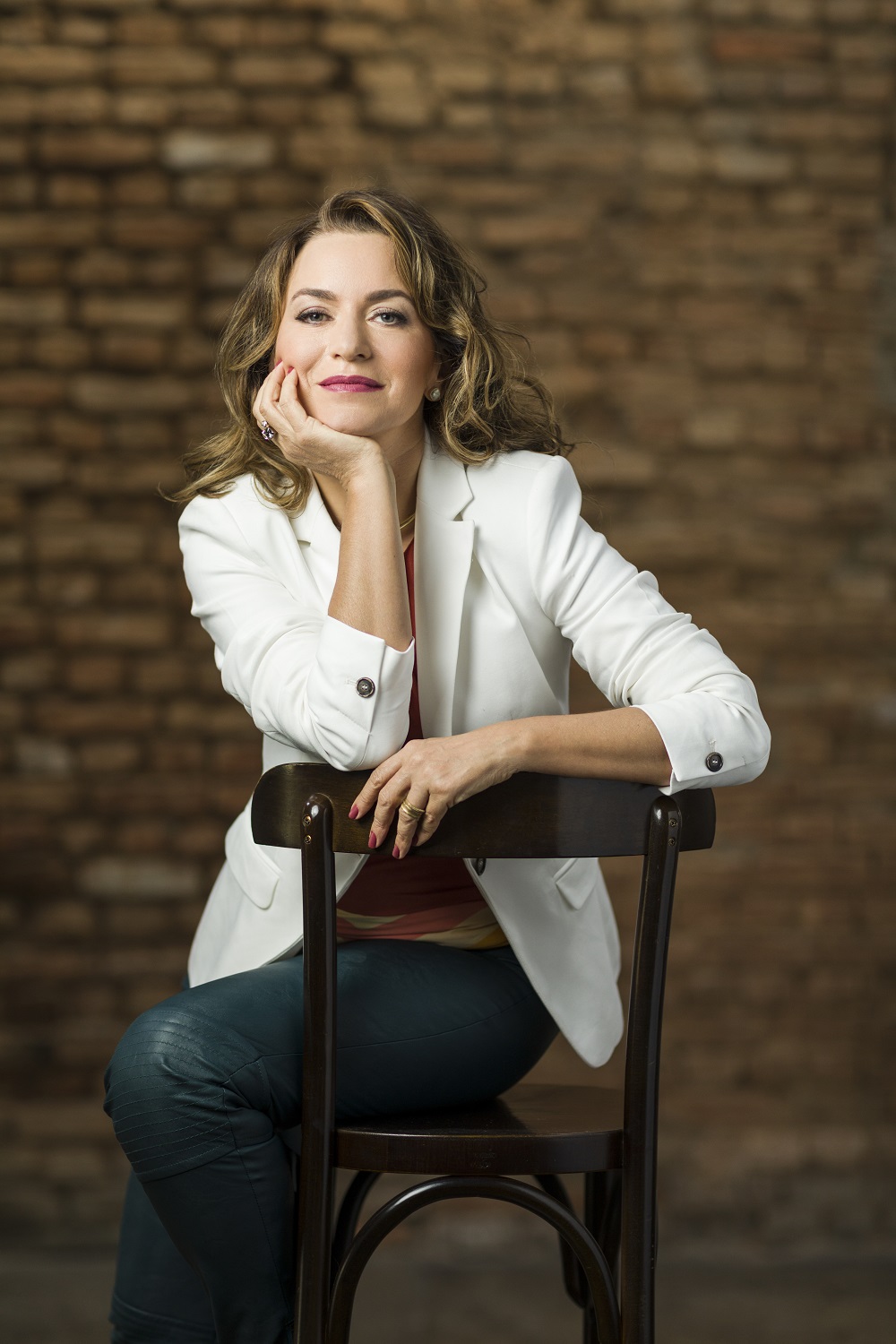 Luciana está sentada em uma cadeira com o rosto encostado na mão