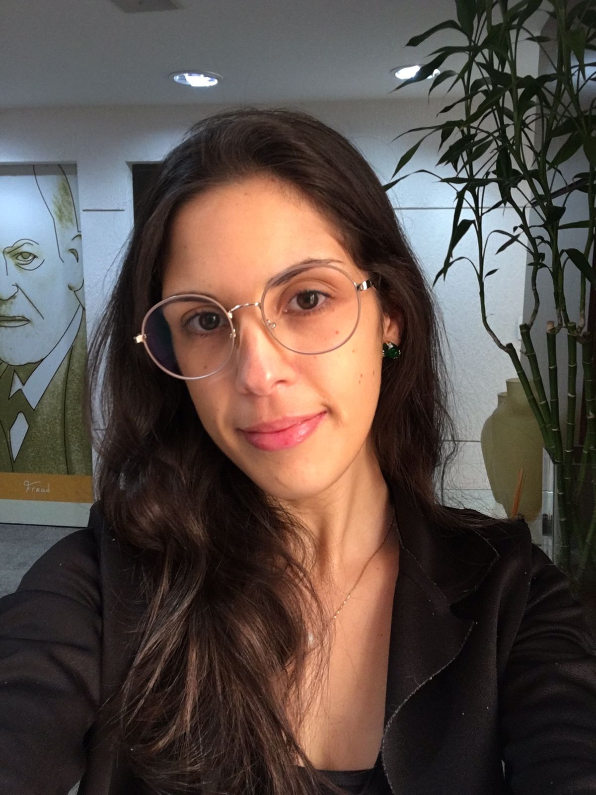 Marilia usa óculos de grau, olha para frente e sorri