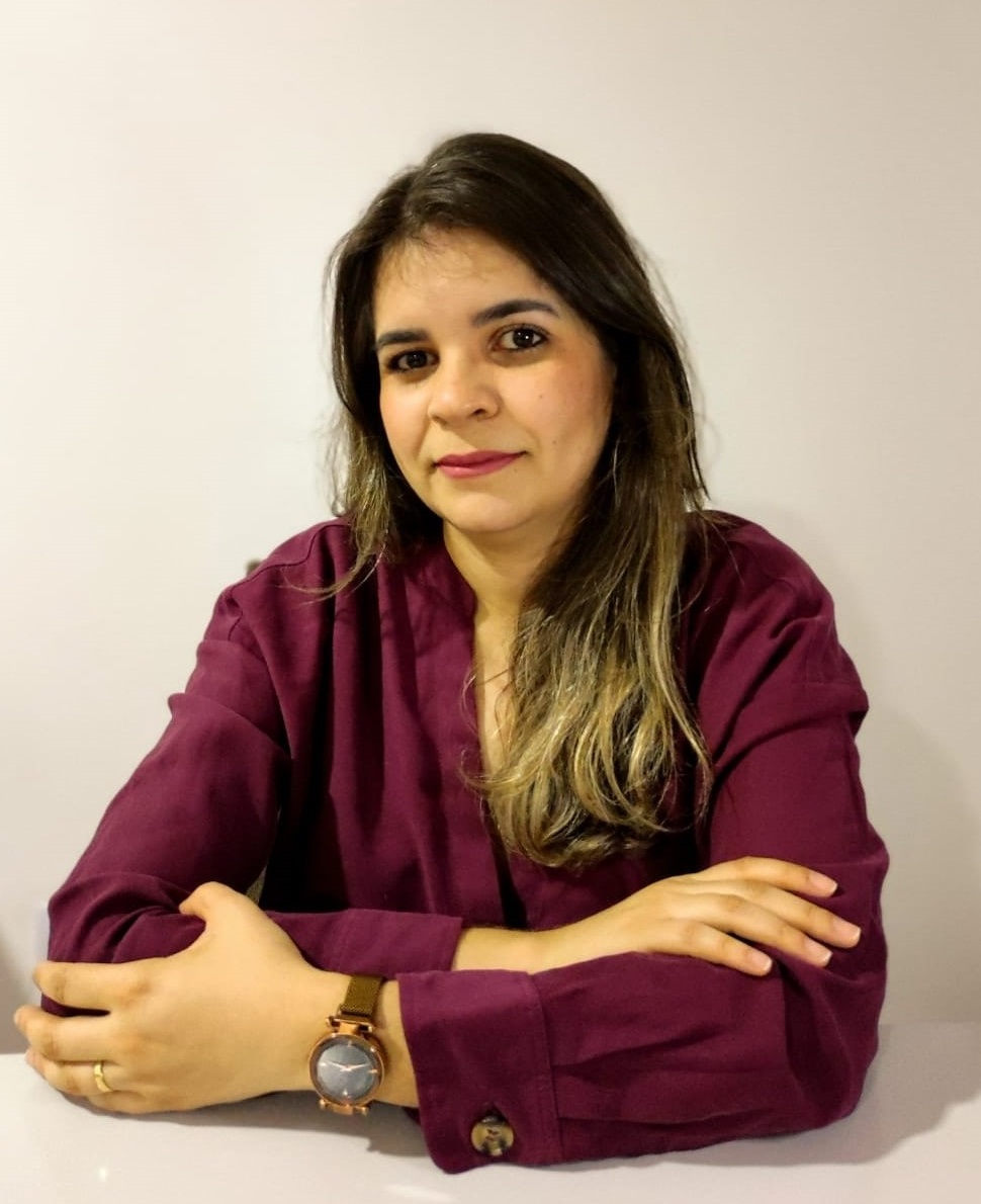 mariele está sentada, olha para frente e sorri discretamente 